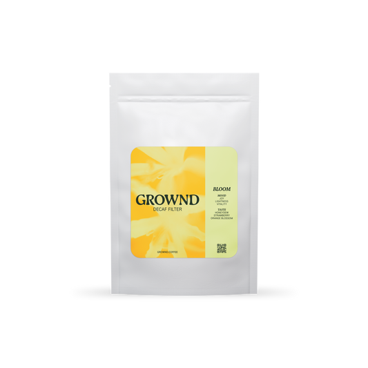 19grams GROWND BLOOM Filter Decaf – Freigestellter weißer Kaffeebeutel mit gelbem Blüten-Label, Geschmacksnoten Honigmelone, Erdbeere und Orangenblüte