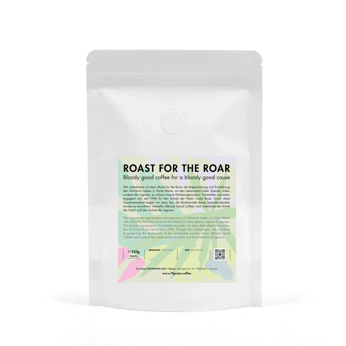 Weißer Kaffeebeutel mit grünem und rosa Etikett, Aufschrift "Roast for the Roar" und Espresso-Hinweis.