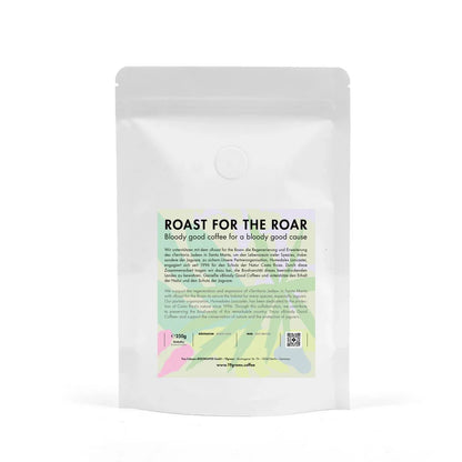 Weißer Kaffeebeutel mit grünem und rosa Etikett, Aufschrift "Roast for the Roar" und Espresso-Hinweis.